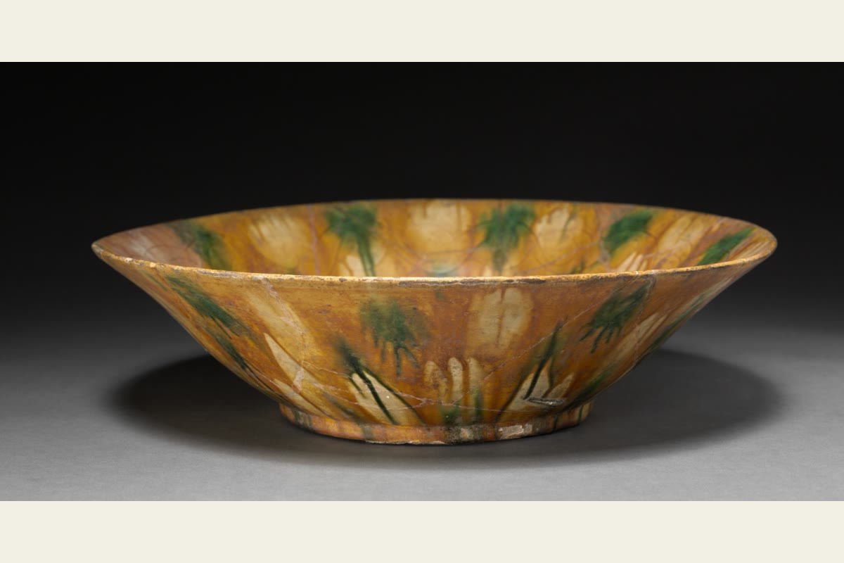 A wide ceramic bowl streaked with yellow, brown and green glaze.