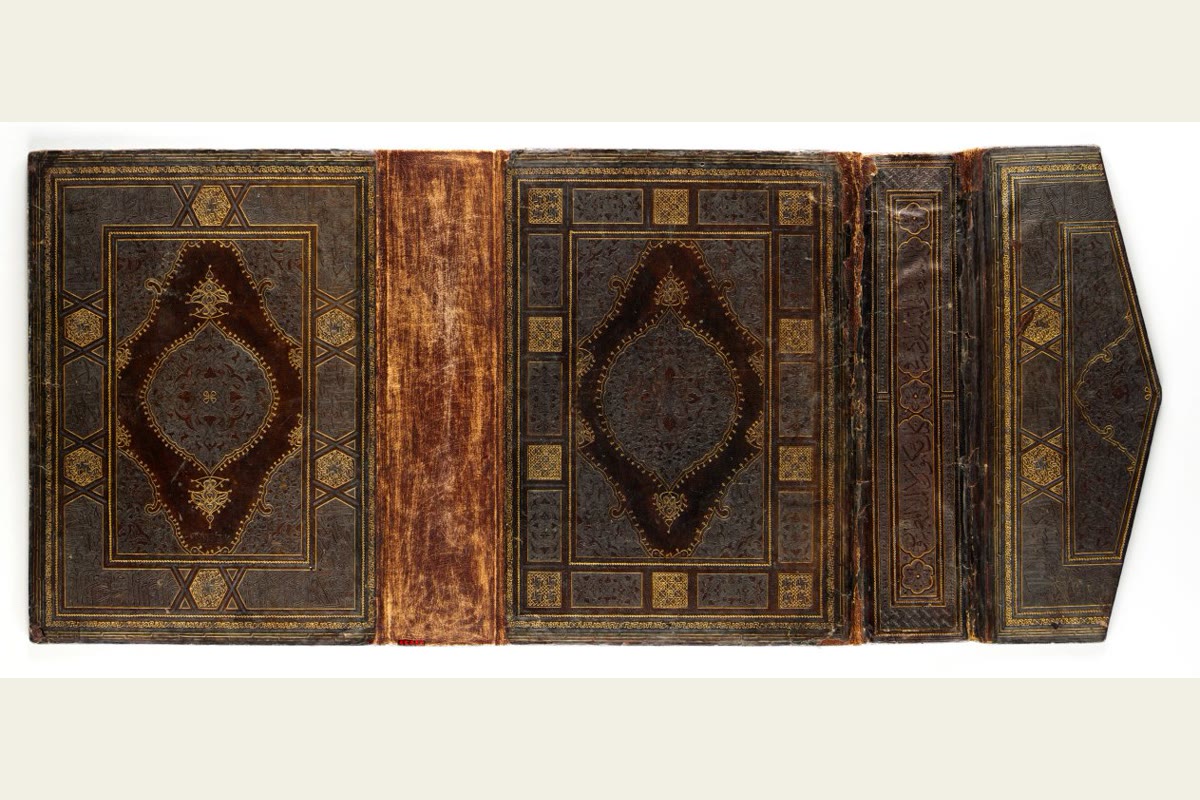 An open Ottoman Quran binding with leather covers, central medallions, intricate borders and an envelope flap.