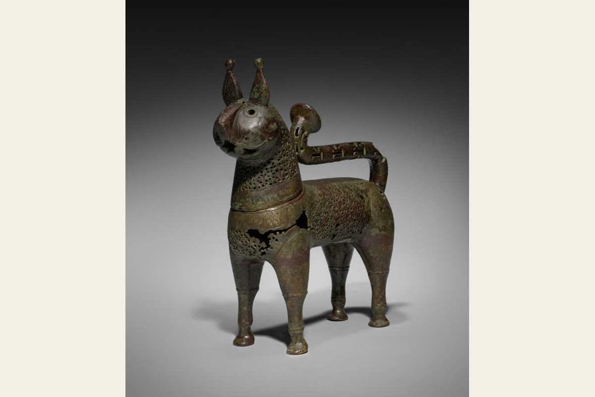 A bronze feline incense burner with pointed ears, slender legs and a pierced decorative body.
