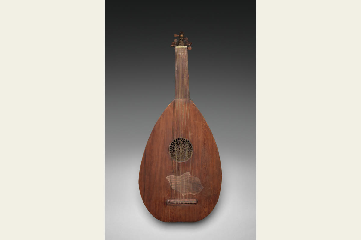 A wooden oud with a broad pear-shaped body, short neck, sound hole and angled peg box.