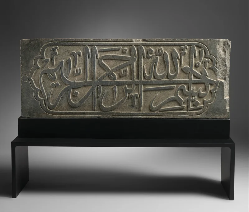 The Bismillah carved in flowing Thuluth letters across a dark basalt panel.